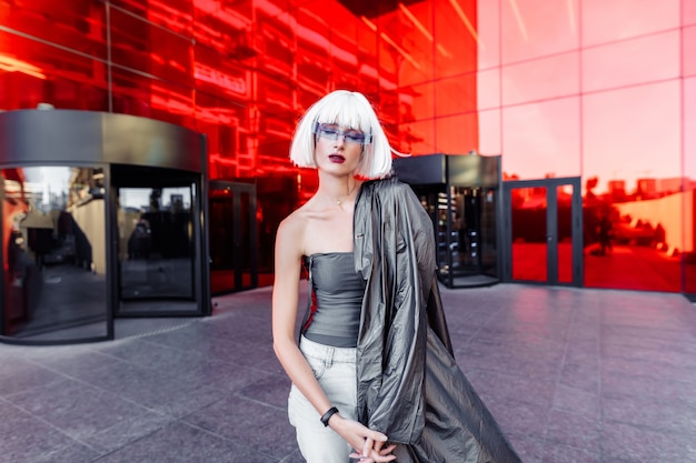 Style futuriste. Femme à lunettes et près d'un bâtiment futuriste rouge.