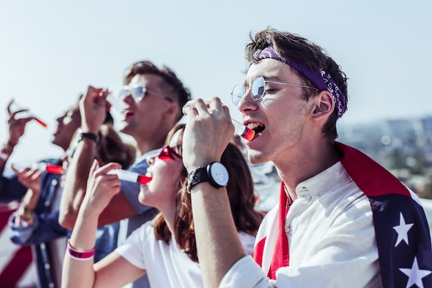 Sur le style. Groupe de jeunes qui font la queue et boivent un cocktail rouge