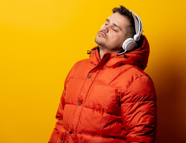 Style homme en veste des années 90 avec un casque sur le mur jaune