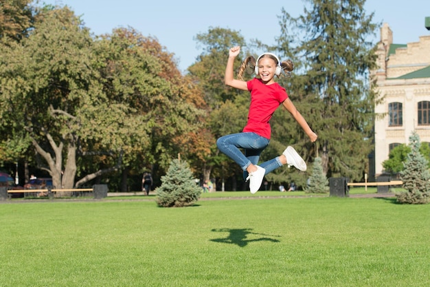 Style de saut de danse. Bonne danseuse. Petite danseuse sautant en musique sur l'herbe verte. Le petit enfant aime danser sur de la musique moderne. Enfant énergique dansant avec plaisir. Vacances d'été.