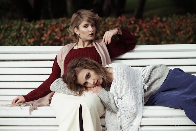 style de vie bonheur émotionnel et les gens concept belles jeunes femmes assises sur un banc dans le parc d'automne