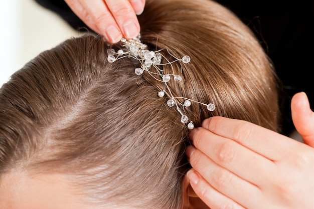 Styliste épinglant la coiffure d&#39;une mariée