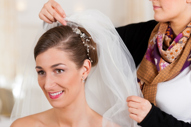 Photo styliste épinglant la coiffure d'une mariée