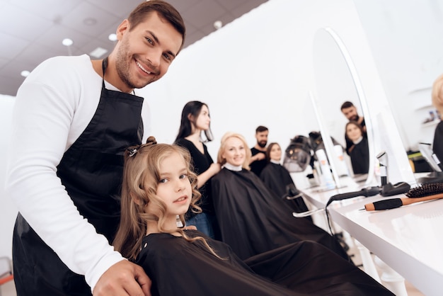 Styliste femme fait la coupe de cheveux de petite fille aux cheveux bouclés.