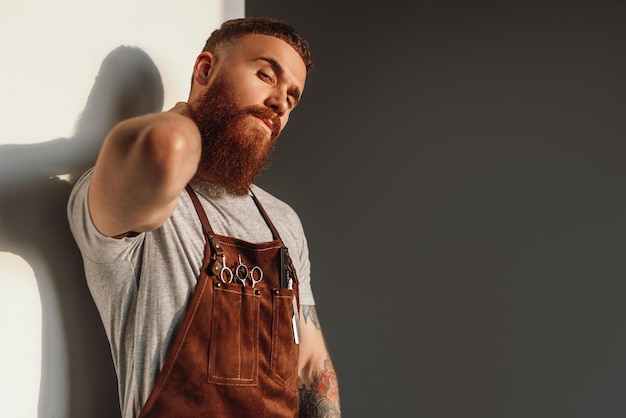 Photo styliste masculin caressant la barbe et regardant la caméra