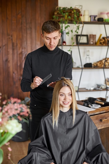 Photo le styliste masculin confiant est la teinture des cheveux d'une cliente blonde caucasienne