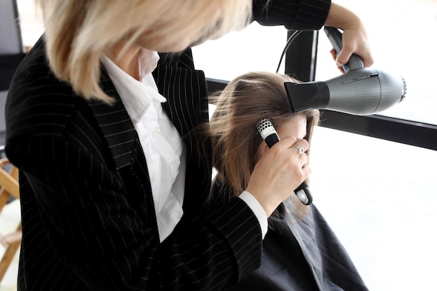 Styliste séchant les cheveux de la femme dans le salon