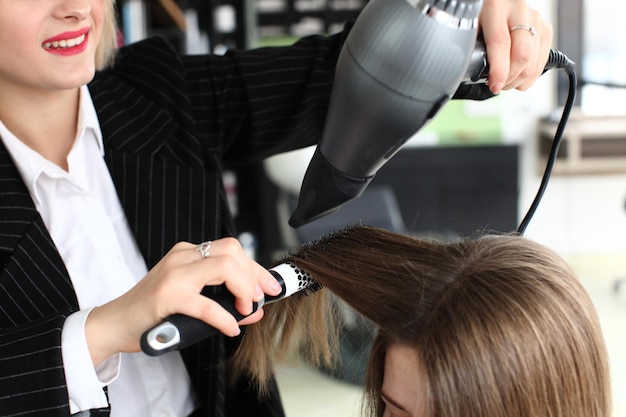 Styliste séchant les cheveux de la femme dans le salon