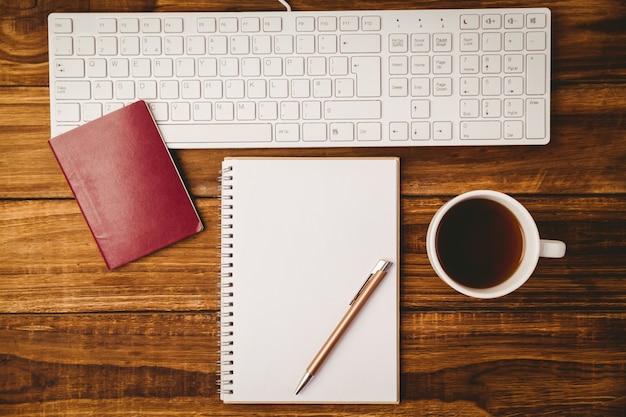 Stylo sur le bloc-notes à côté d&#39;une tasse de passeport et d&#39;un clavier