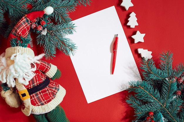 Stylo et bloc-notes rouges sur la table rouge décorée d'une branche de sapin le fond pour le texte