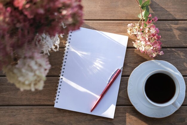 Stylo bloc-notes et tasse à café sur une table en bois Faire une liste de tâches ou une liste de courses Liste de lecture de liste de souhaits