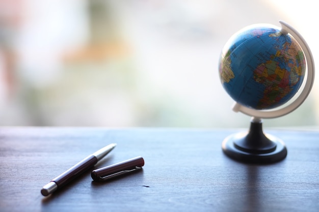 Un stylo sur le bureau et un petit globe bleu