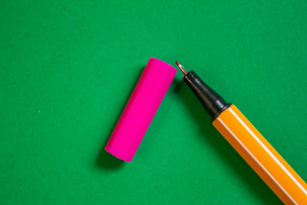 Photo un stylo jaune et orange avec un stylo sur fond vert