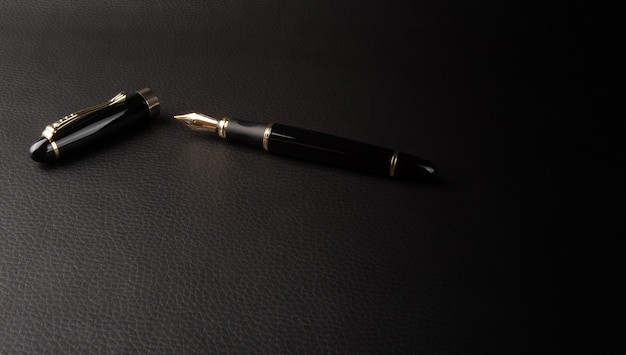 Stylo plume, beaux détails d'un beau stylo plume, placé sur cuir noir, mise au point sélective.