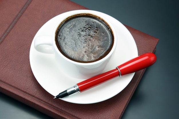 Le stylo rouge est une tasse de soucoupe de café noir