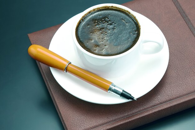 Stylo rouge sur une tasse blanche de café noir. boisson chaude