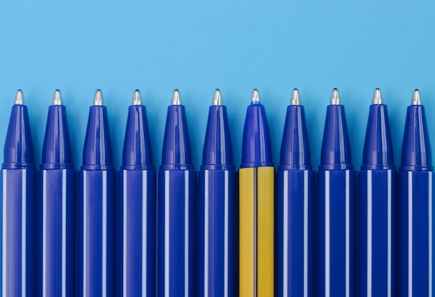 Stylos bleus et un stylo jaune sur fond bleu