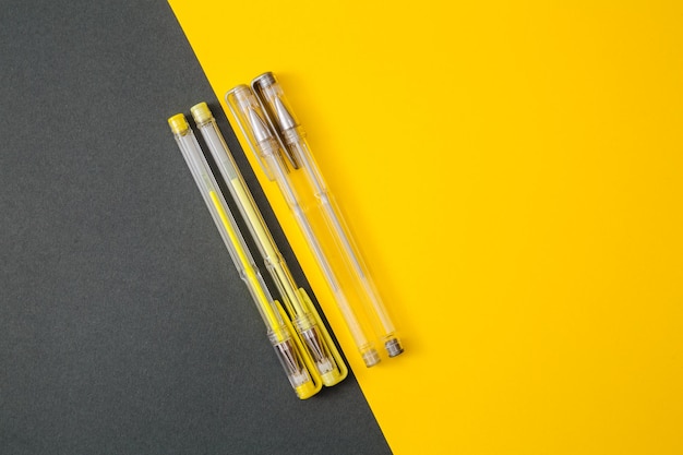 Stylos gel jaune et gris sur fond jaune et gris