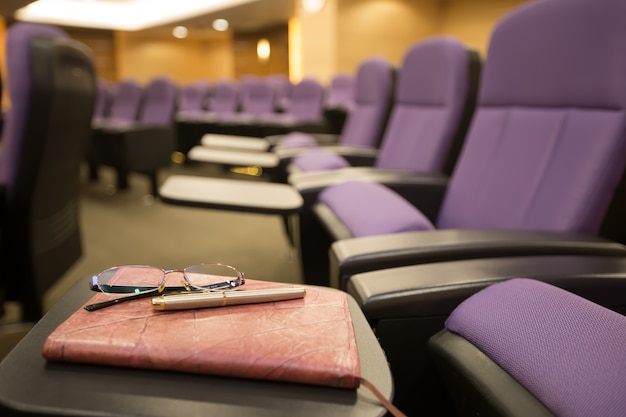 Stylos, lunettes et cahiers dans la salle de réunion.