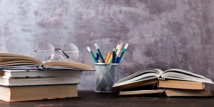 Photo stylos, pomme, crayons, livres et verres sur la table