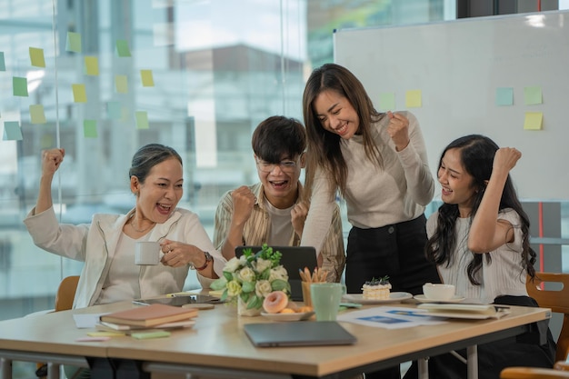 Succès et concept de travail d'équipe Groupe de partenaires commerciaux avec les mains levées dans un poste de travail moderne léger célébrant la percée dans leur entreprise