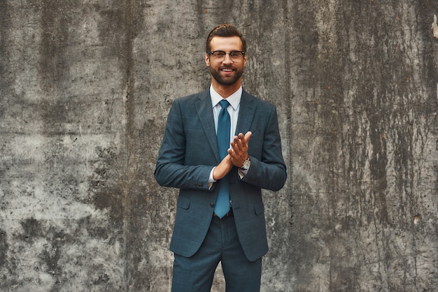 Succès dans tout homme d'affaires barbu confiant et heureux en costume complet se frottant les paumes et