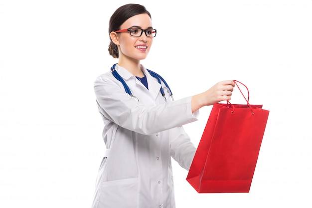Succès jeune femme médecin avec stéthoscope donnant sac à provisions en uniforme blanc sur blanc
