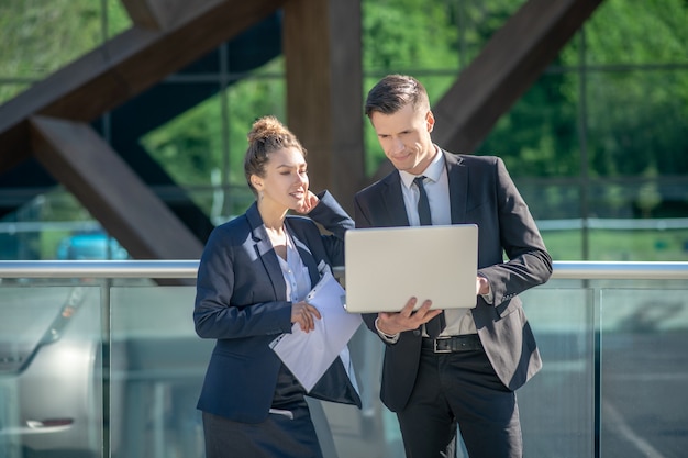 Succès et jeune homme avec ordinateur portable femme avec document sur rue