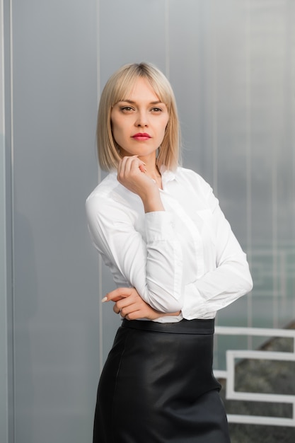 Succès De Jolie Jeune Femme En Chemise Blanche Et Jupe Noire Debout Sur Fond Gris.