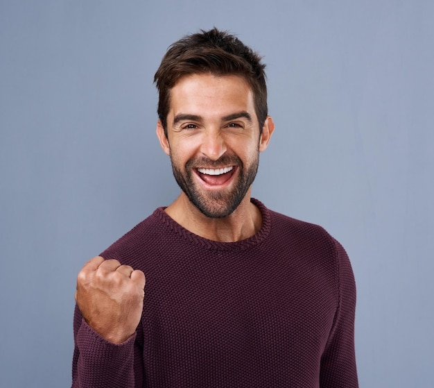 Succès poing et homme heureux sur le fond du studio avec célébration réalisation ou oui pour la compétition de bonus ou la loterie gagnant excité dans le portrait avec le pouvoir et la motivation pour les nouvelles ou l'opportunité