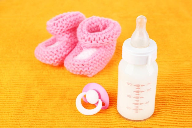 Sucette de bouteille de lait pour bébé et chaussons pour bébés sur fond jaune