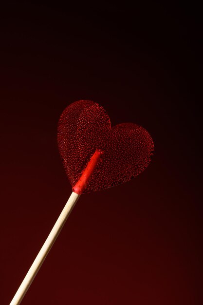 Une sucette rouge transparente en forme de cœur sur un fond rouge foncé Love Banner pour la Saint-Valentin