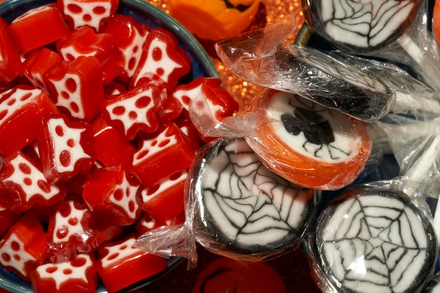 Sucettes d'araignée et bonbons de crâne d'halloween sur fond orange vif