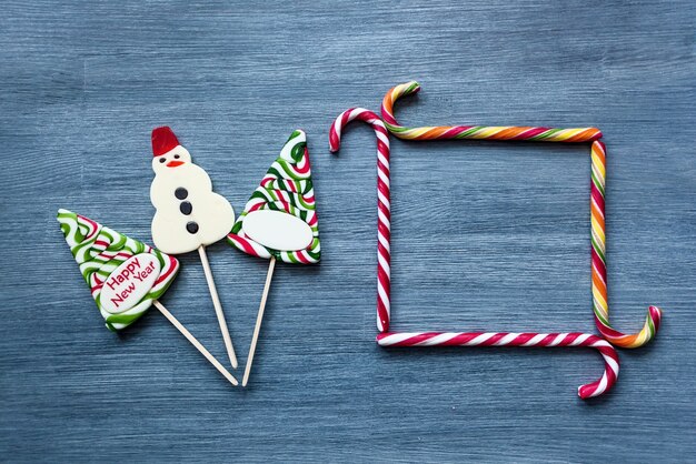 Sucettes de bonbons colorés Bonbons du Nouvel An sur fond bleu. Arbre de Noël, sucettes et bonhomme de neige. Sweet sucker, le doux cadre de bâtons de bonbons