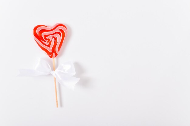 Sucettes en forme de coeur sur un bâton avec un arc blanc sur fond blanc Carte de voeux Saint Valentin Espace pour copier Vue de dessus en position plate