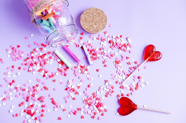 Sucettes en forme de coeur Petits papiers en rouleau coeurs et un pot sur fond violet Pot à souhaits pour la Saint Valentin