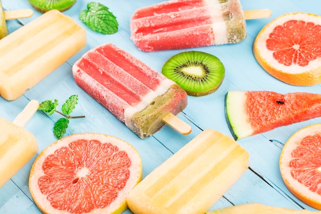 Sucettes glacées aux fruits entiers sains avec cantaloup de pastèque aux baies Kiwi sur table vintage en bois