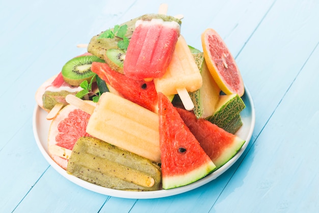 Sucettes glacées aux fruits entiers sains avec cantaloup de pastèque aux baies Kiwi sur table vintage en bois