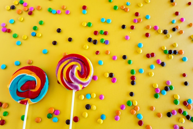 Sucettes pour enfants et chocolats colorés sur fond jaune