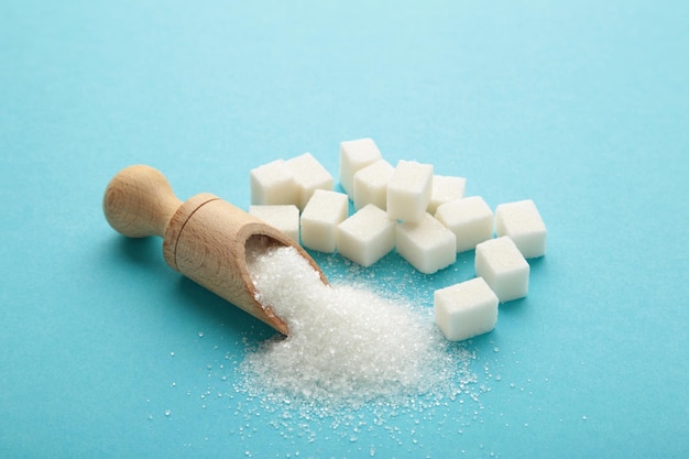 Sucre blanc dans une cuillère en bois sur fond bleu