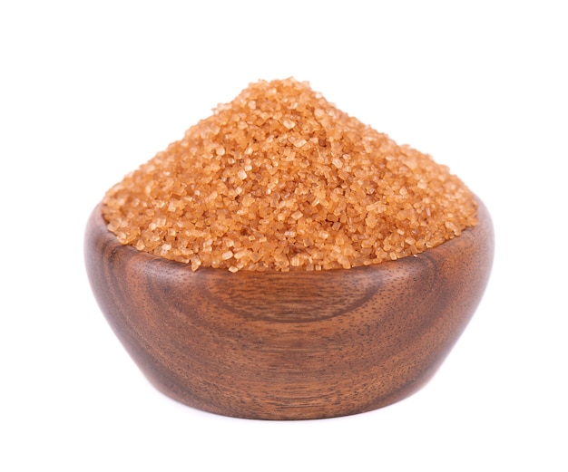 Sucre brun dans un bol en bois isolé sur fond blanc tas de cristaux de sucre de canne