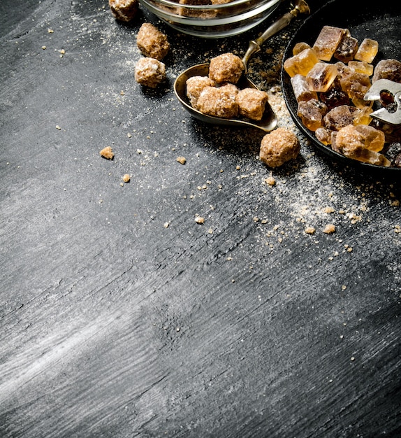 Sucre de canne brun. Sur une table rustique noire.