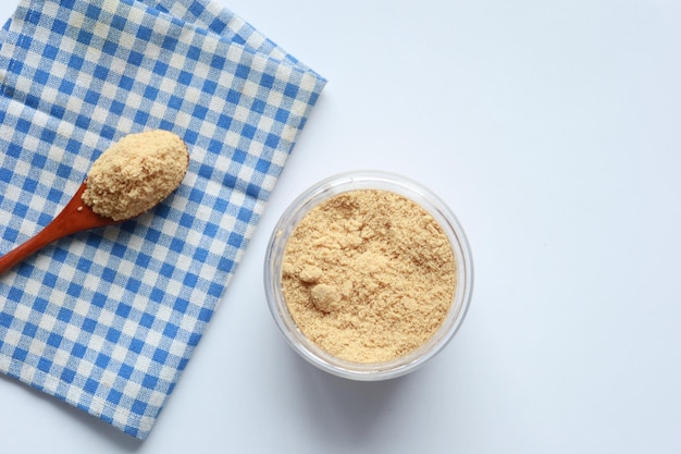 Sucre de coco dans un récipient sur fond blanc