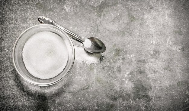 Sucre et cuillère. Sur une table en pierre.