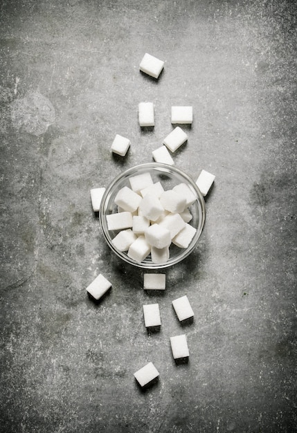 Sucre raffiné dans une soucoupe en verre. Sur un fond de pierre.