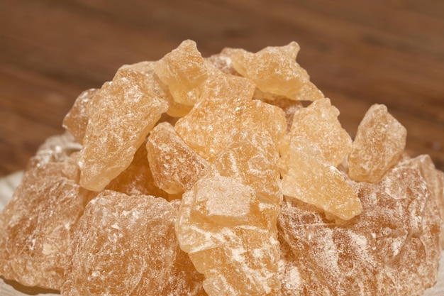 Le sucre de roche dans le récipient est sur la table de grain de bois