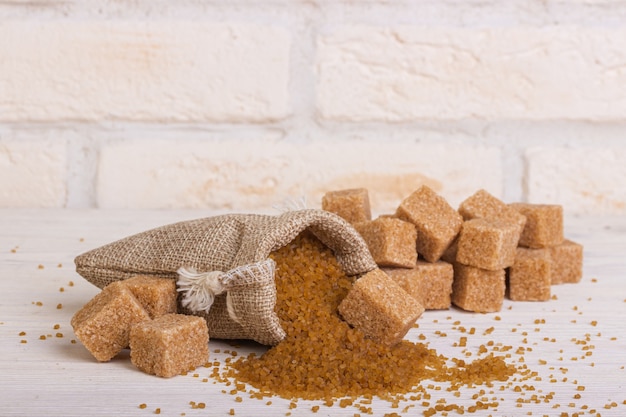 Sucre Throsy sous forme de cubes et de sable dans un sac et une cuillère en bois