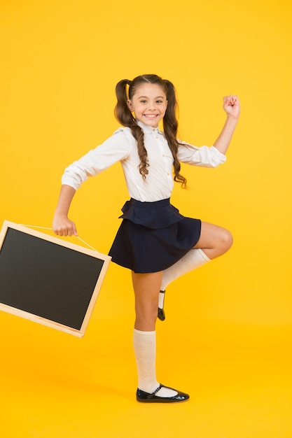 Suivez-moi Élève d'écolière informant Une écolière tient un espace de copie de tableau blanc Annonce et promotion L'uniforme scolaire de fille tient un tableau noir pour retourner au concept de l'école Faire l'étape