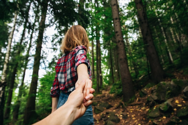 Suivez-moi photo dans les montagnes. Femme élégante en chemise à carreaux. Notion d'envie d'errance. Couple randonnée et voyage en été. Tenir la main dans la nature.