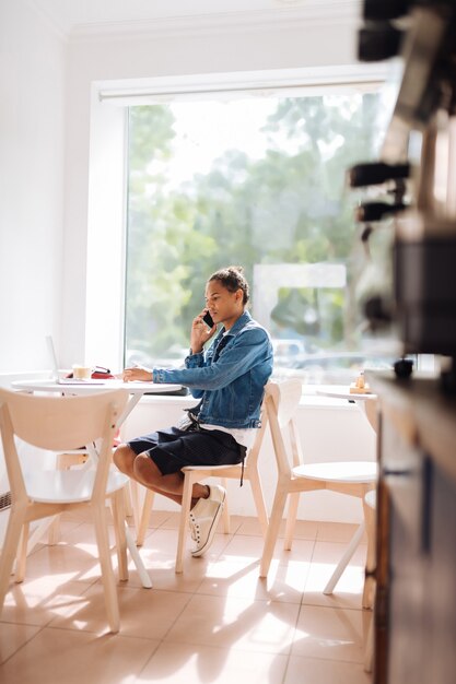 Suivez votre entreprise. Jeune homme sérieux assis dans un café et regardant son ordinateur portable